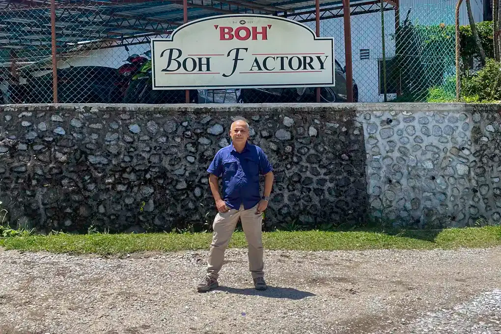 Anuar at Habu BOH Tea Plantation, Cameron Highlands Anuar standing beside the BOH Factory sign at Habu BOH Tea Plantation in Cameron Highlands.