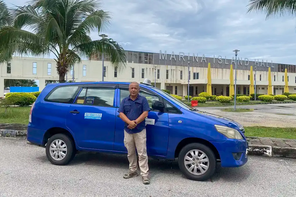 Anuar beside the My Little Taxi Toyota Innova at Marina Island in Lumut after a customer drop-off