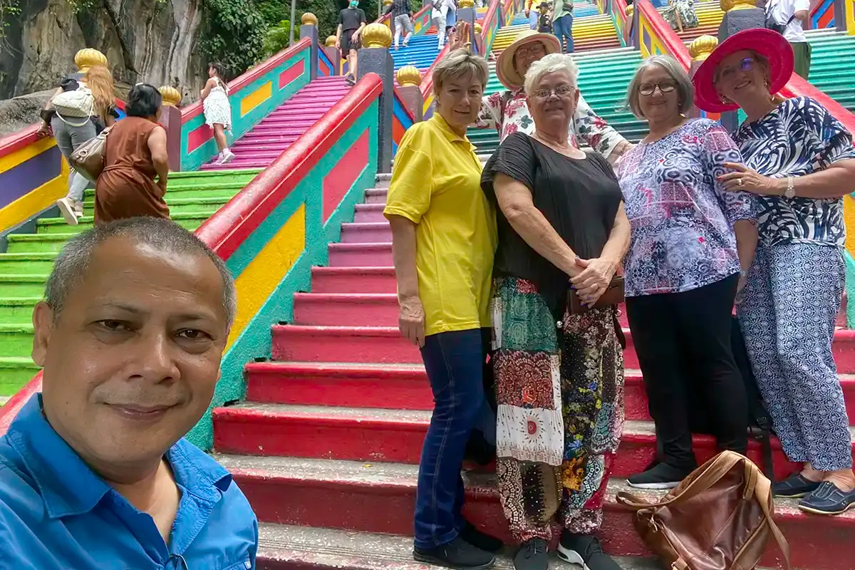 Anuar posing with a group of visitors on the colourful staircase at Batu Caves near Kuala Lumpur.