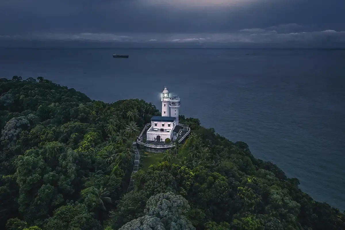 Aerial view of Cape Rachado Lighthouse surrounded by coastal forest near Port Dickson, Malaysia