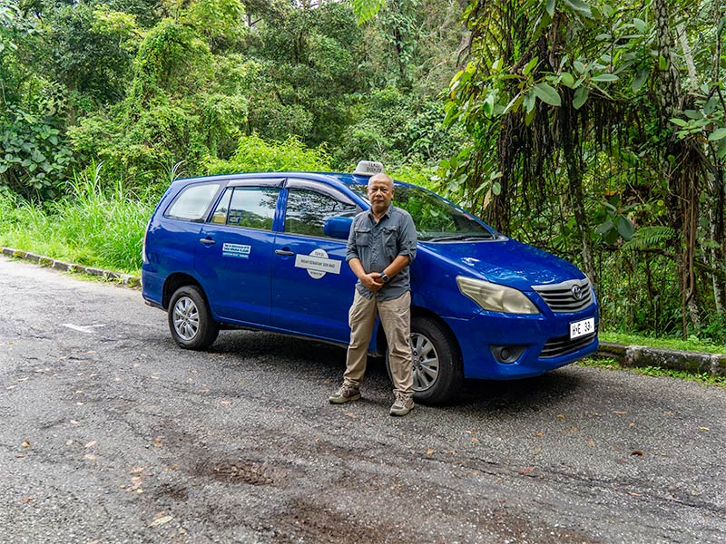 Home 1 Anuar — My Little Taxi private transfer
driver based in Kuala Lumpur, standing
beside a Toyota Innova MPV