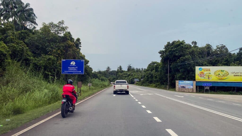 Road approaching Cherating with the Club Med Cherating turn-off sign and turtle conservation centre sign on the Kuantan-Kemaman road