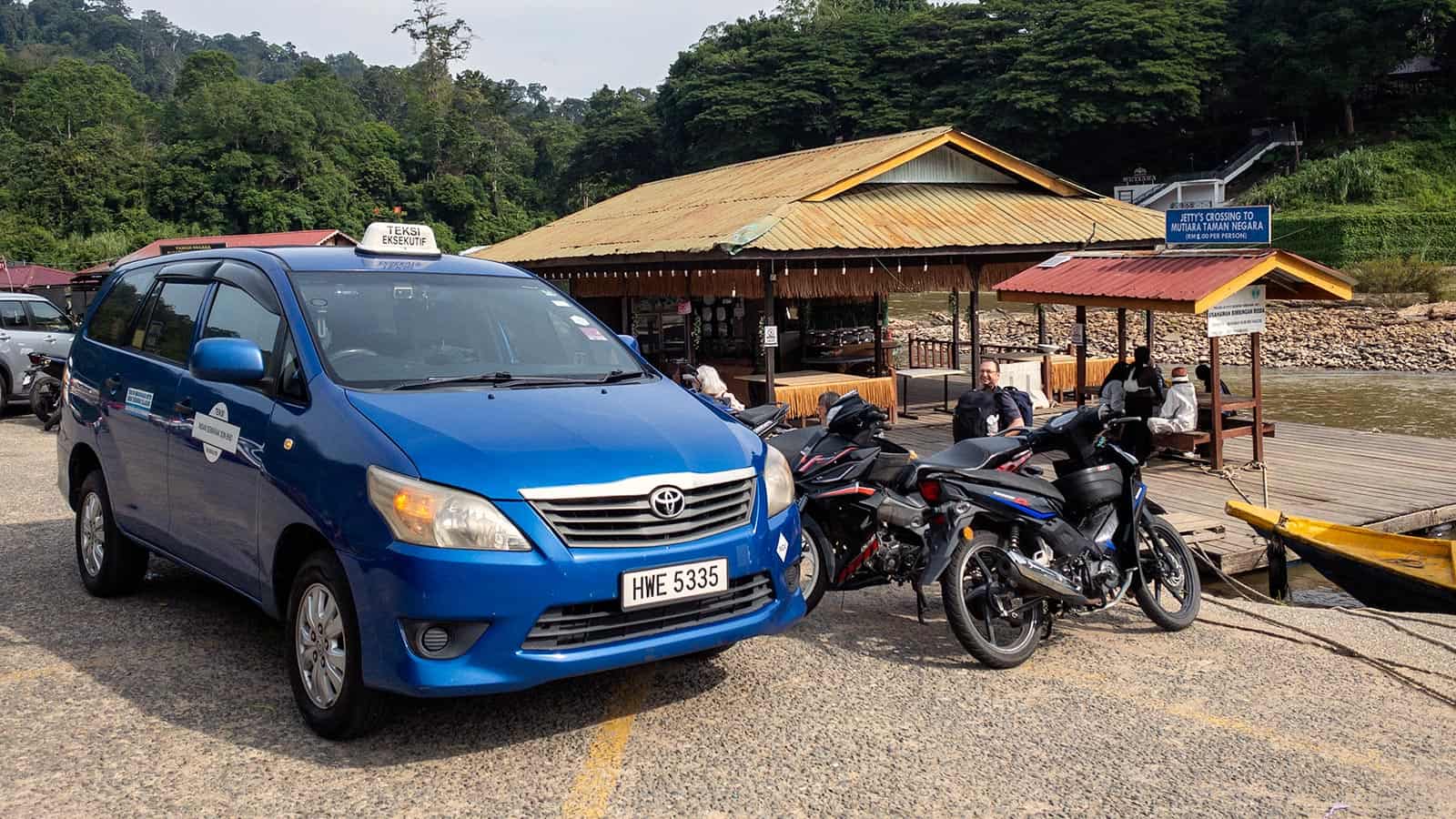 "Kuala Lumpur to Taman Negara private transfer — blue Toyota Innova at the Kuala Tahan jetty crossing
